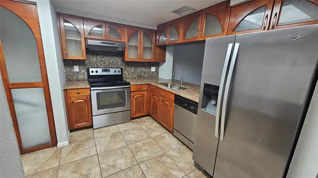 a kitchen with stainless steel appliances granite countertop a refrigerator a stove and a sink