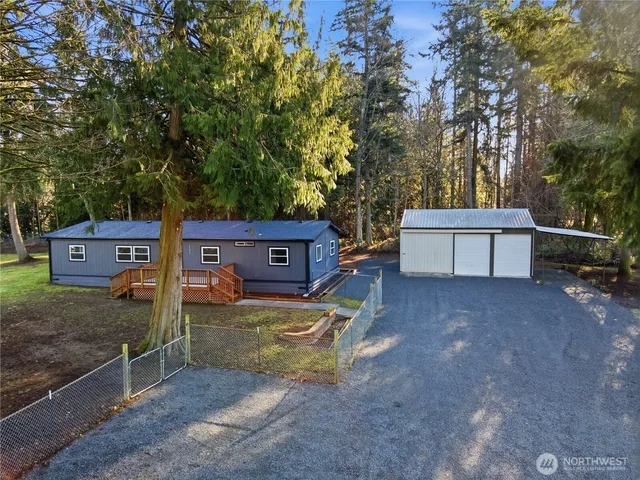 a view of a backyard with large trees and a wooden fence