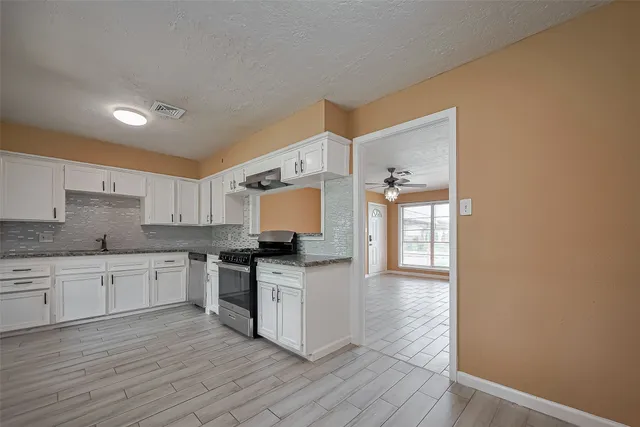 a kitchen with stainless steel appliances granite countertop a stove top oven a sink a counter space and cabinets