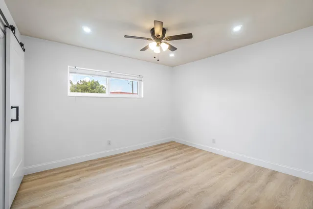 an empty room with wooden floor and ceiling fan
