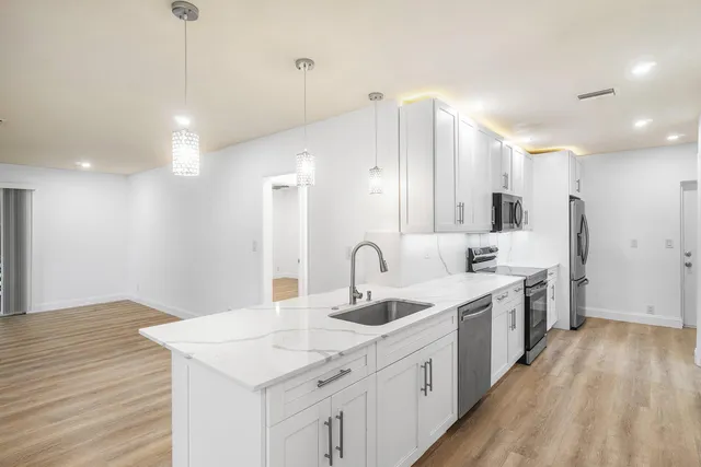 a large kitchen with a sink and wooden floor