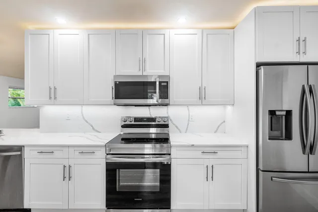 a kitchen with white cabinets and stainless steel appliances
