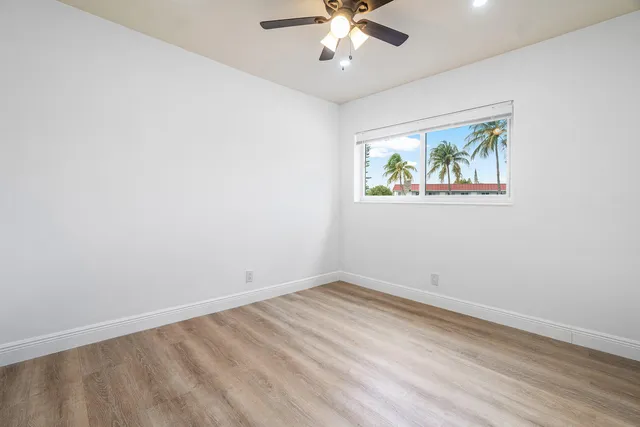 an empty room with windows and fan