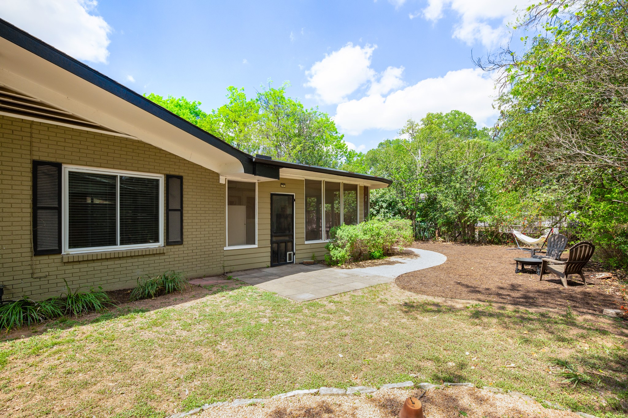 4702 Lasso Path Austin, TX 78745 - Photo 14 of 31 View of grassy yard with a patio area, a sunroom, and an outdoor fire pit
