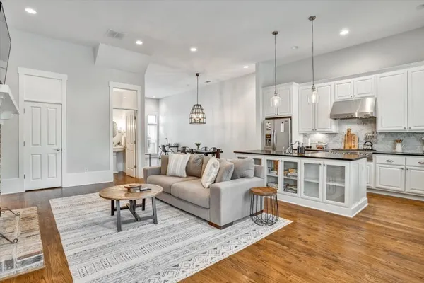 a living room with furniture kitchen area and a wooden floor