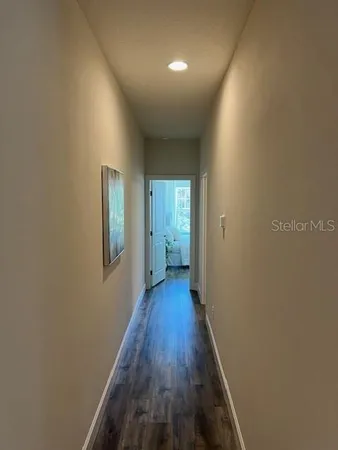 a view of a hallway with wooden floor and a bathroom