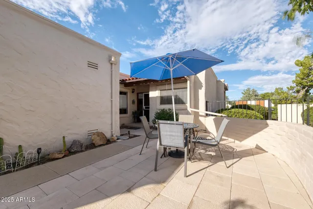 a view of a patio with a table and chairs under an umbrella