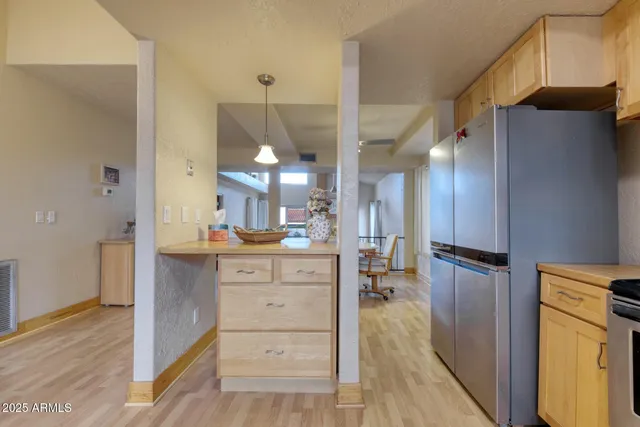 a kitchen with stainless steel appliances kitchen island granite countertop a refrigerator a stove and a sink with wooden floor