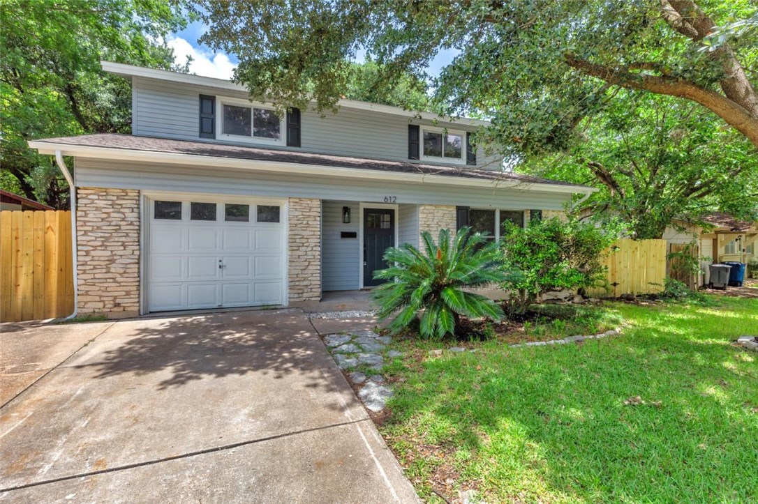 a front view of a house with a garden and trees