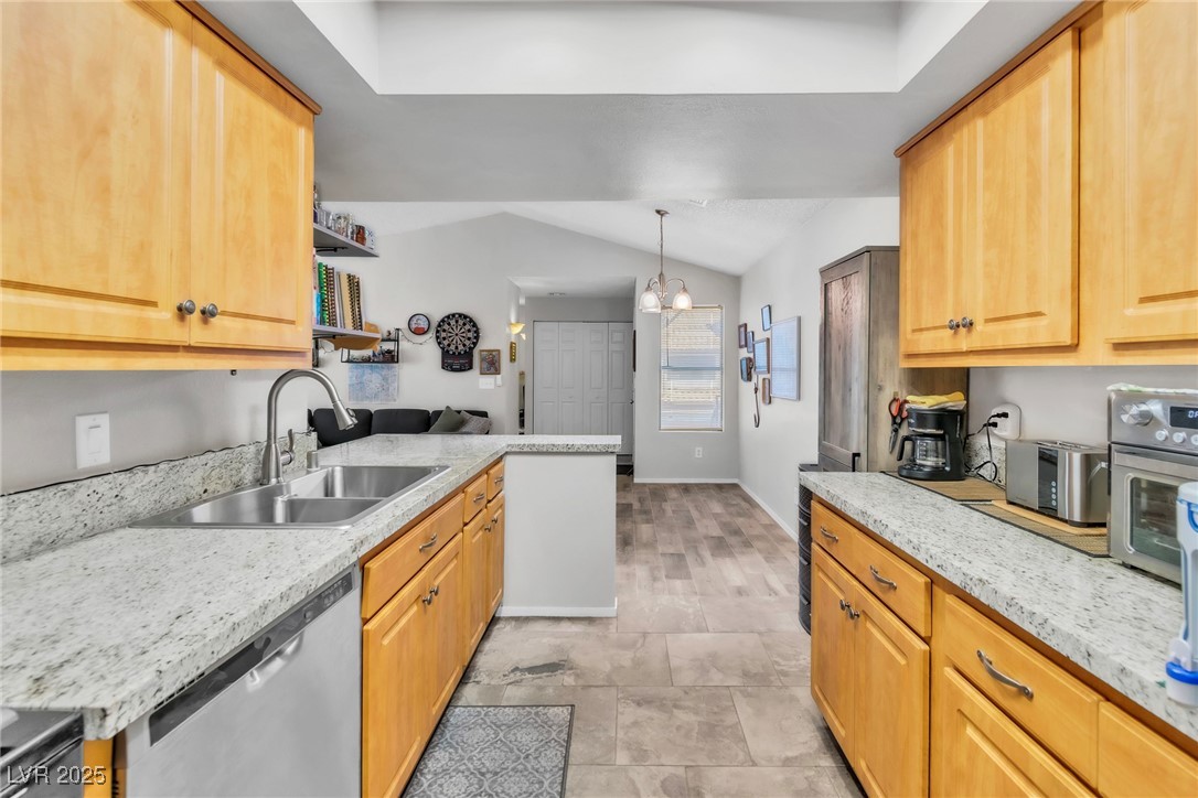 2995 East Sunset Road, Unit 235 Las Vegas, NV 89120 - Photo 6 of 24 Kitchen featuring stainless steel dishwasher, vaulted ceiling, a chandelier, a peninsula, and light stone counters