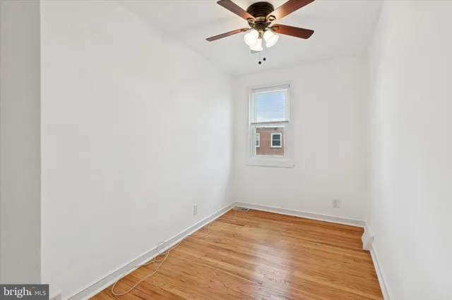 an empty room with wooden floor and fan