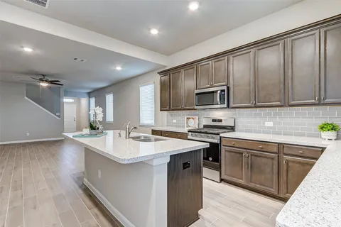a kitchen with a sink stove cabinets and wooden floor