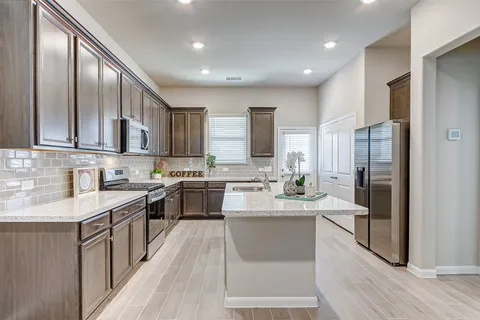 a large kitchen with stainless steel appliances lots of counter space and a sink