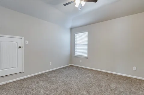 an empty room with a chandelier fan and windows