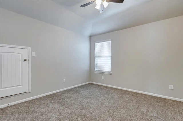 an empty room with a chandelier fan and windows