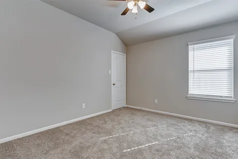 an empty room with a chandelier fan and windows