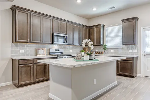 a kitchen with kitchen island granite countertop a sink stove and cabinets