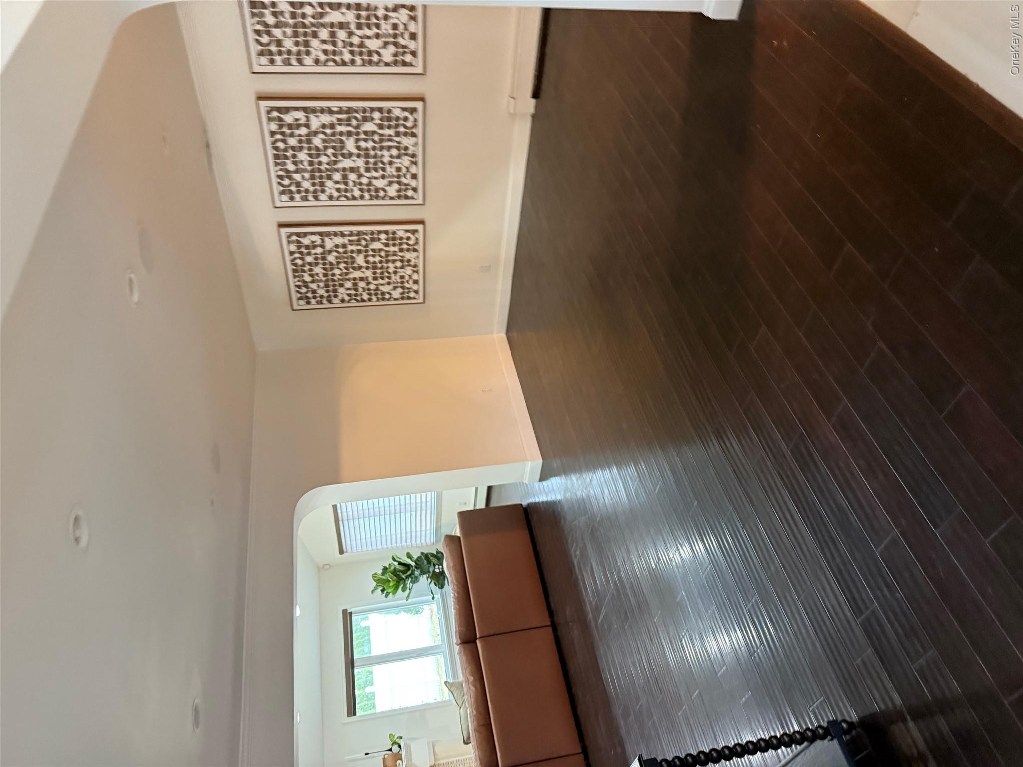 29 Wilton Road Rye Brook, NY 10573 - Photo 15 of 18 Unfurnished living room featuring a baseboard heating unit, arched walkways, baseboards, and wood finished floors