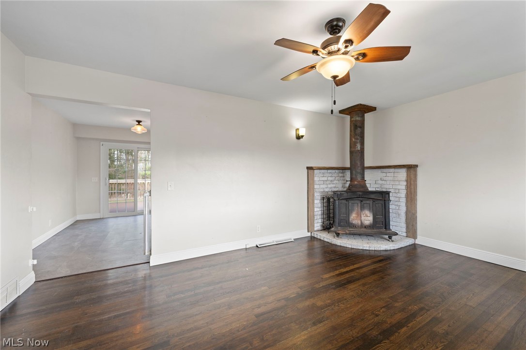 1835 Windham Road Newton Falls, OH 44444 - Photo 7 of 40 Unfurnished living room featuring dark wood-type flooring, a ceiling fan, and a wood stove