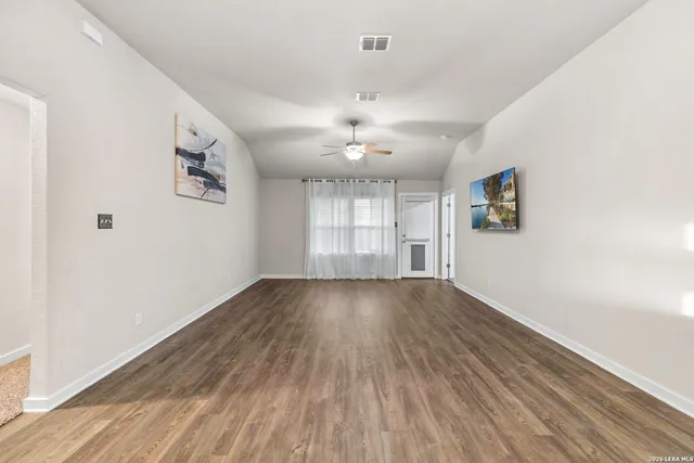 an empty room with wooden floor and windows