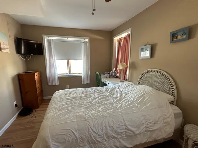 a bedroom with a bed wooden floor and television