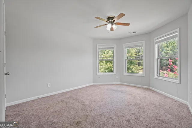 an empty room with windows and chandelier fan