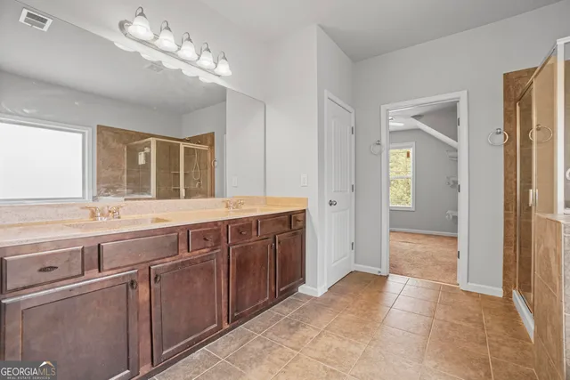 a spacious bathroom with a granite countertop double vanity and a mirror