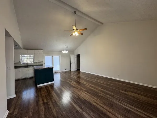 a view of kitchen and empty room with wooden floor