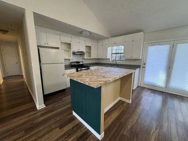 a kitchen with a stove a refrigerator and wooden floor