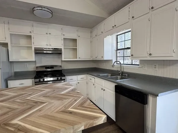 a kitchen with granite countertop a sink stove and cabinets