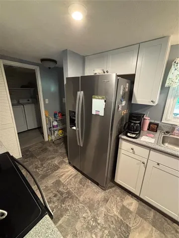 a view of a refrigerator in kitchen and an empty room