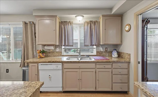 a dining room with stainless steel appliances granite countertop a refrigerator a stove a sink dishwasher a dining table and chairs with wooden floor