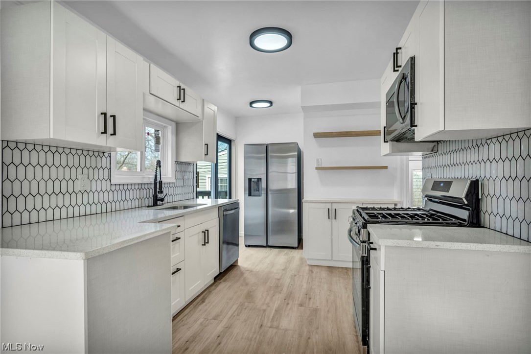 932 Englewood Road Cleveland Heights, OH 44121 - Photo 13 of 32 Kitchen featuring light wood-type flooring, white cabinets, tasteful backsplash, sink, and stainless steel appliances