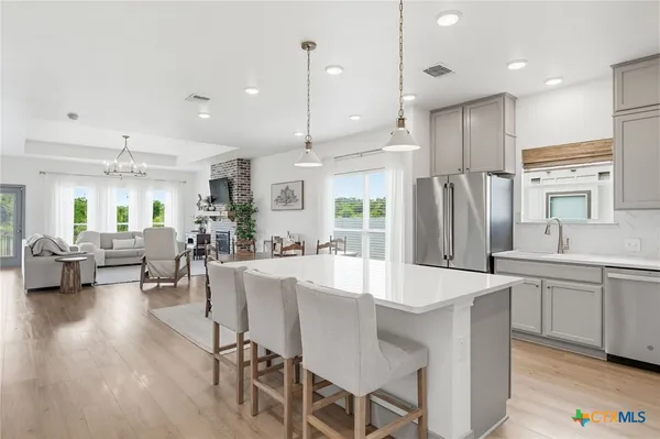 a kitchen with stainless steel appliances granite countertop a refrigerator a sink dishwasher a stove and a refrigerator with wooden floor