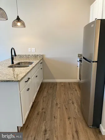a view of a kitchen with a sink wooden floor and a refrigerator