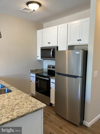 a kitchen with granite countertop a refrigerator sink and stove