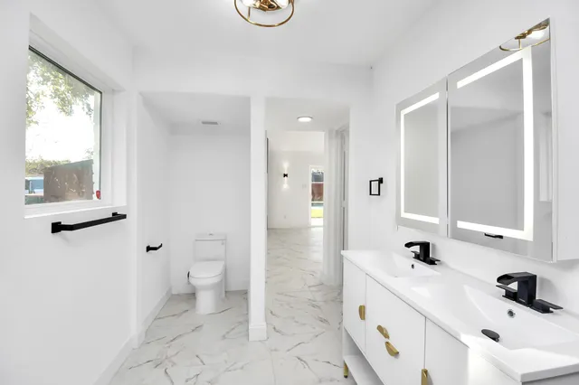 a bathroom with a sink a toilet and a large mirror