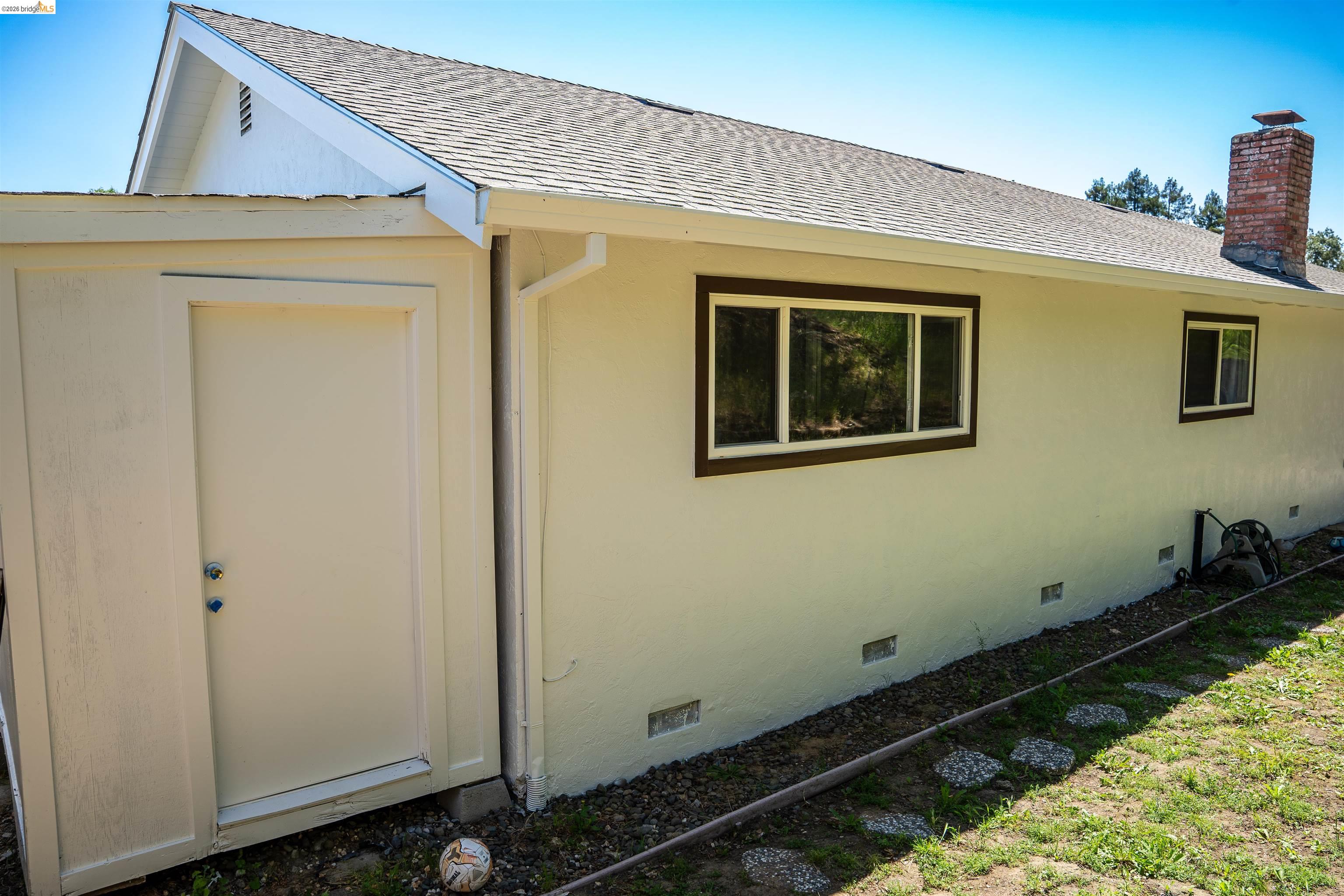 64 Washington Street Novato, CA 94947 - Photo 19 of 21 Exterior featuring a brick chimney, a light-colored stucco facade, and dark-trimmed windows