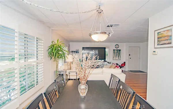 a view of a dining room and livingroom with furniture wooden floor a chandelier