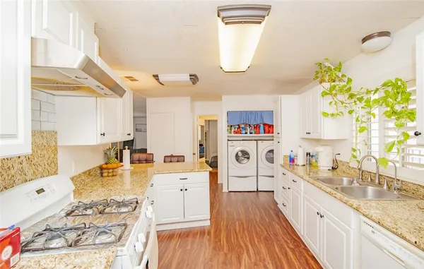 a very nice looking open kitchen with granite countertop a sink a stove and a wooden floors