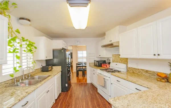 a large kitchen with stainless steel appliances a lot of counter space sink and wooden floor