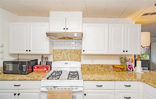 a kitchen with granite countertop white cabinets and white appliances