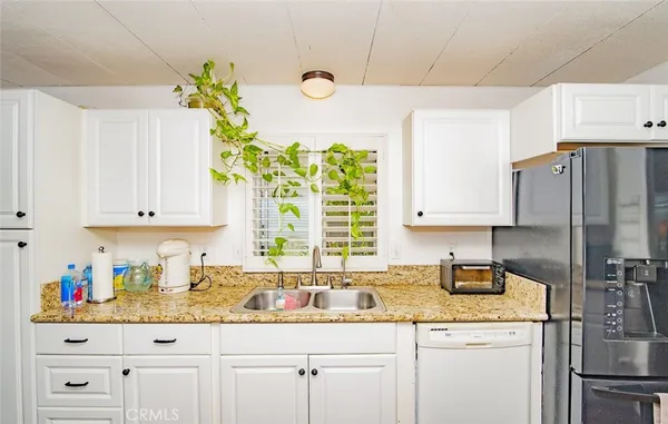 a kitchen with stainless steel appliances white cabinets a sink and a refrigerator