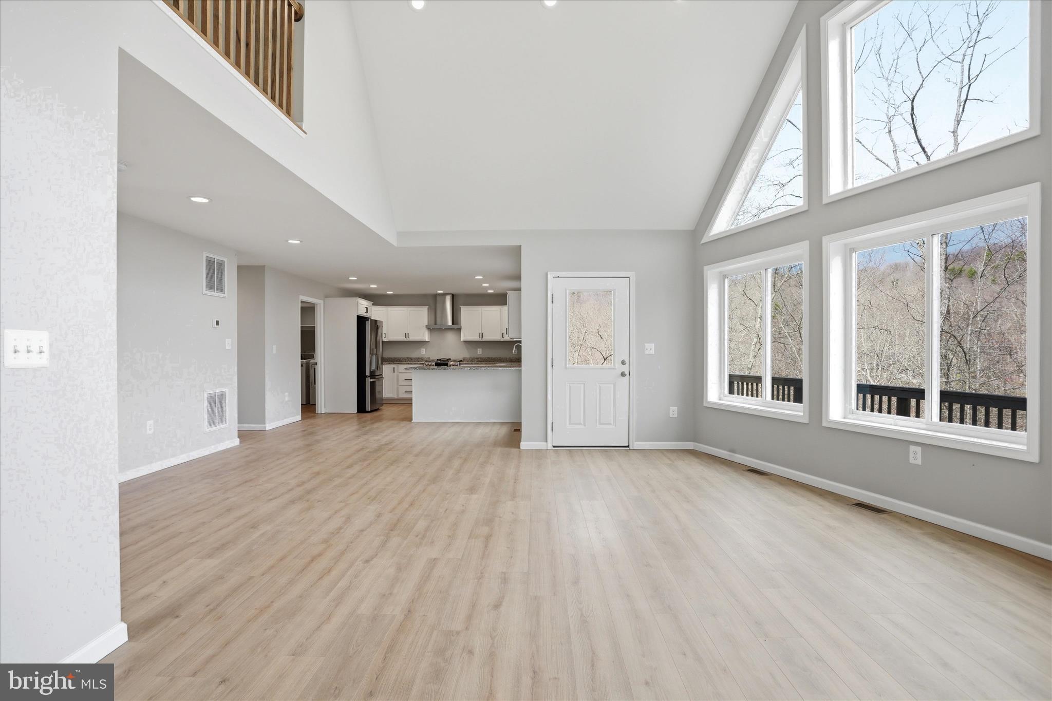 490 Black Twig Road Linden, VA 22642 - Photo 9 of 44 a view of empty room with wooden floor and a kitchen
