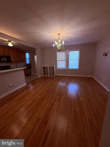 a view of a room with wooden floor and a kitchen