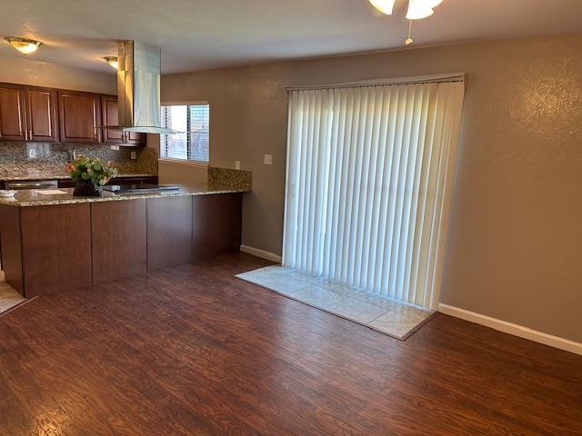 5500 Ragan Drive The Colony, TX 75056 - Photo 10 of 17 Kitchen with baseboards, island exhaust hood, decorative backsplash, and wood finished floors