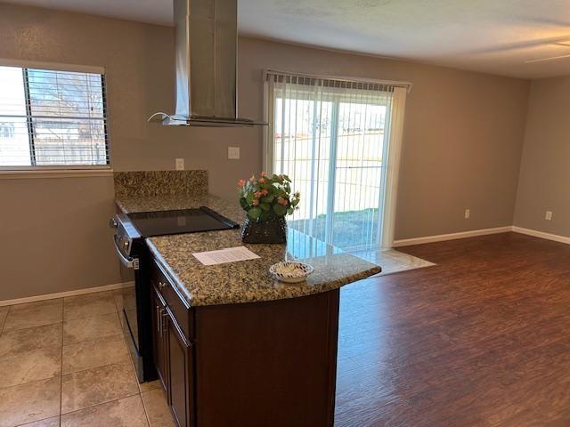 5500 Ragan Drive The Colony, TX 75056 - Photo 2 of 17 Kitchen featuring stone countertops, baseboards, black range with electric cooktop, and wall chimney exhaust hood