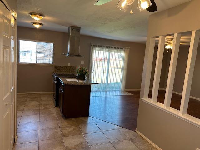 5500 Ragan Drive The Colony, TX 75056 - Photo 5 of 17 Kitchen featuring ceiling fan, wall chimney exhaust hood, range with electric stovetop, and a wealth of natural light
