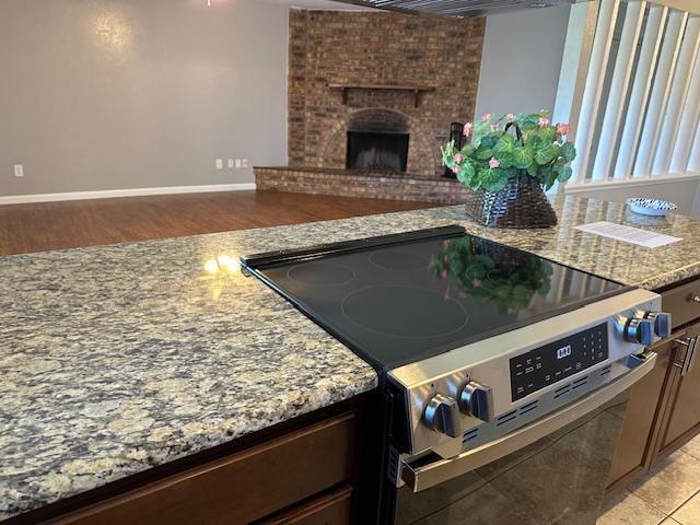 5500 Ragan Drive The Colony, TX 75056 - Photo 17 of 17 Kitchen with light stone counters, a fireplace, baseboards, open floor plan, and stainless steel electric range oven