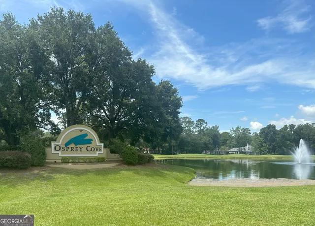 a view of a lake with a yard and large trees